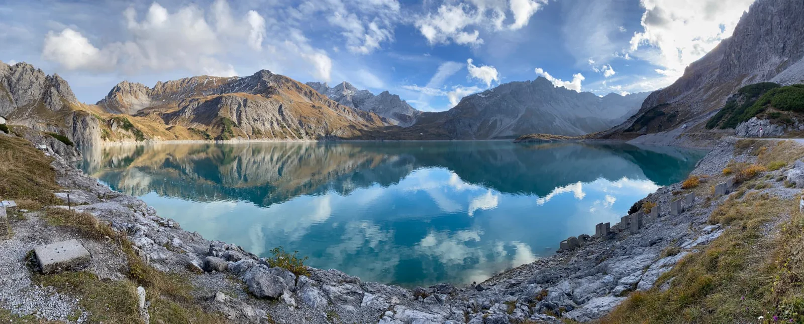 Weiter alpiner See unter blauem Himmel